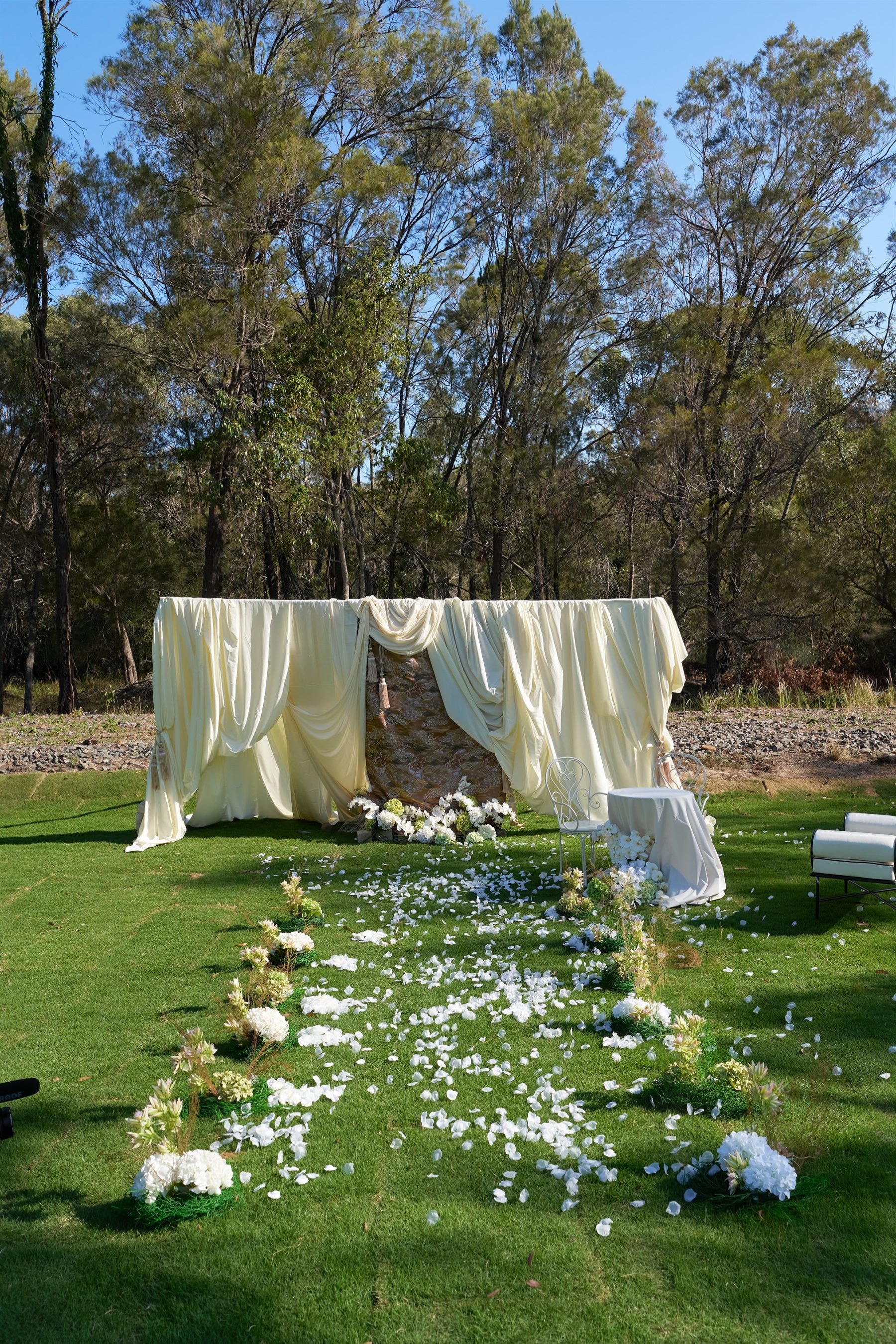 Outdoor ceremony aisle with draped backdrop and French Lite Iron seating